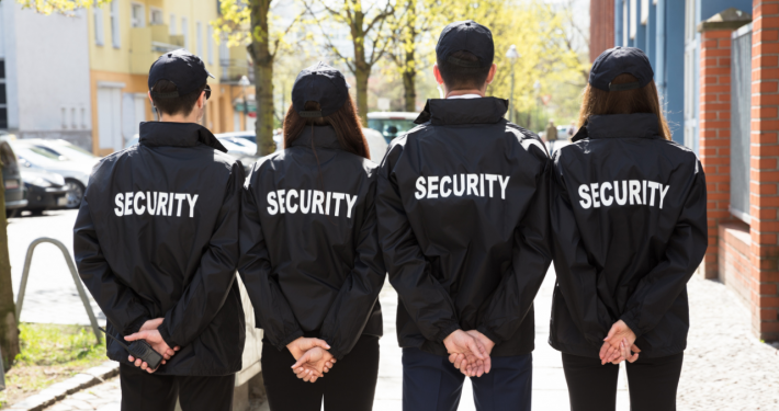 four security guards standing with their faces turned away